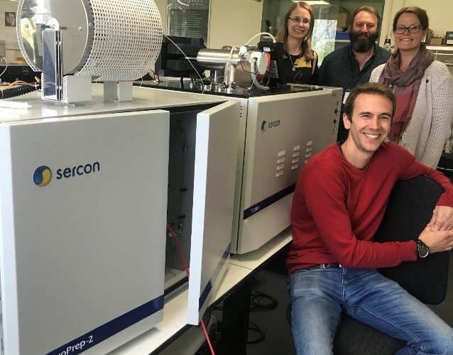 Photo of four people stood next to lab machines