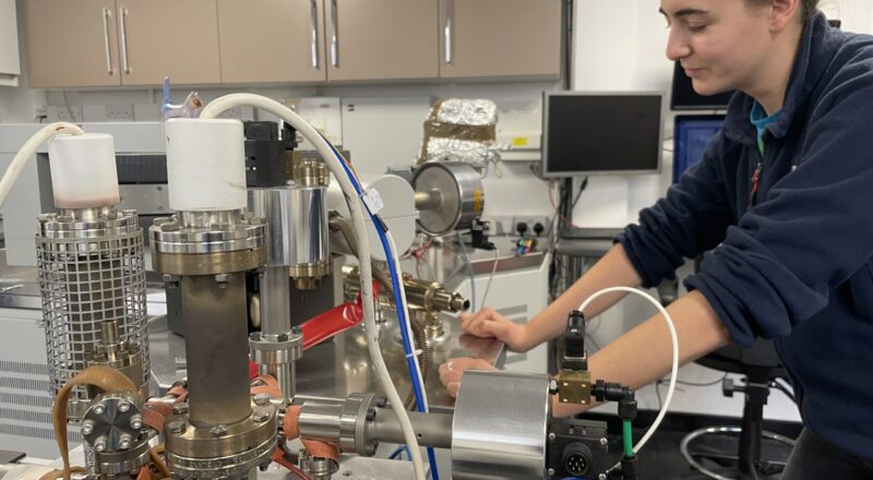 Photo of a woman infront of a Split Flight Tube KMass Spectrometer